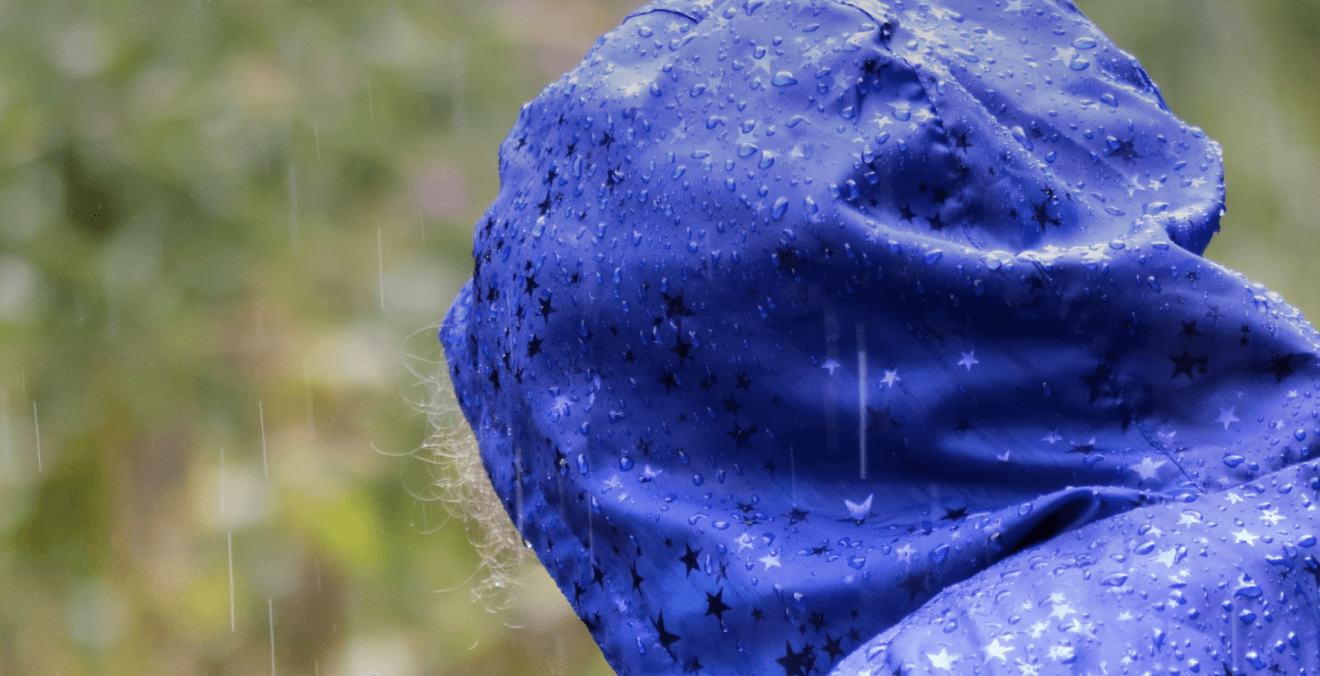 Pessoa vestindo capa de chuva de tecido impermeavel, de costas, dia chuvoso.