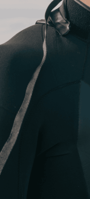 homem vestindo roupa neoprene de surf - recorte da foto mostrando apenas o ombro direito.