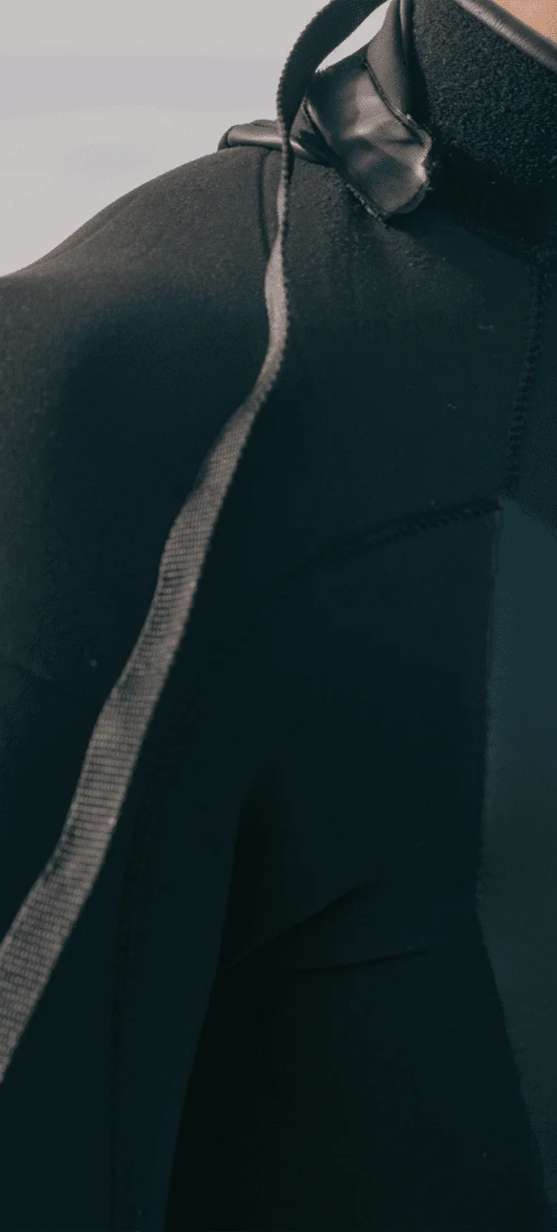 homem vestindo roupa neoprene de surf - recorte da foto mostrando apenas o ombro direito.